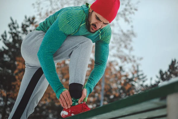 Sportler mit Knöchelschmerzen draußen an einem verschneiten Tag — Stockfoto