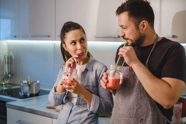 Casal flertando na cozinha enquanto bebe smoothie — Fotografia de Stock