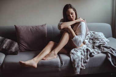 Kanepede oturan uzun bacaklı seksi kız