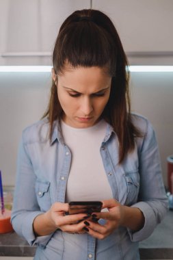 Kızgın kız cep telefonu mutfakta bakıyor