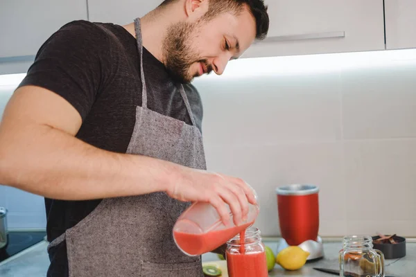 Homem derramando smoothie do liquidificador no frasco — Fotografia de Stock