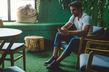 Hipster süre oturan ve hareket eden telefon arayan gülüyor