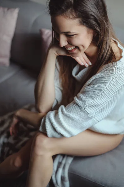 Sexy girl laughing while sitting on a couch — Stock Photo, Image