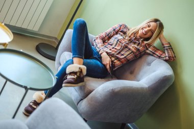 Bir sandalyede oturuyor ve telefon tutarak gülüyor kadın