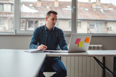 Bir dizüstü bilgisayarda ofiste çalışan ciddi adam