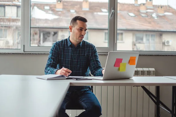 Bir dizüstü bilgisayarda ofiste çalışan ciddi adam