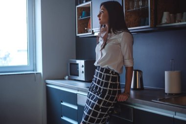 Pencereden bakarak bir mutfak tezgah üzerine eğilerek kız