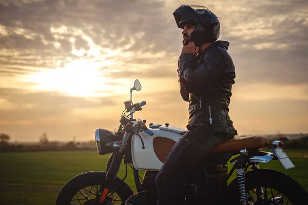 Motosiklet üzerinde oturan ve onun kask koyarak motorcu
