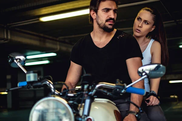 Angry girlfriend talking to her biker boyfriend in a garage — Stock Photo, Image