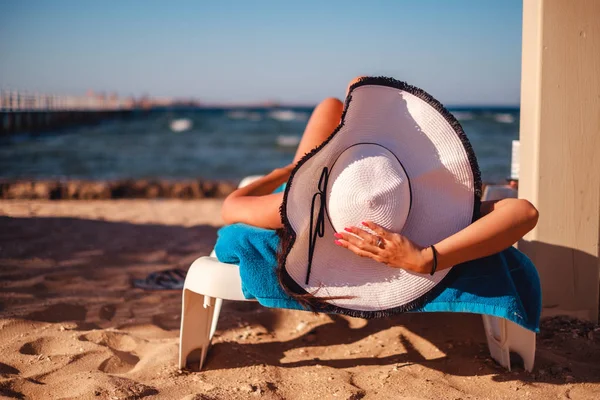 Chica sosteniendo sombrero mientras está acostado en la playa —  Fotos de Stock