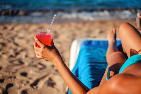 Chica sosteniendo cóctel mientras está acostado en la playa y bronceado —  Fotos de Stock