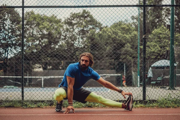 Homem atleta barbudo alongamento perna ao ar livre — Fotografia de Stock