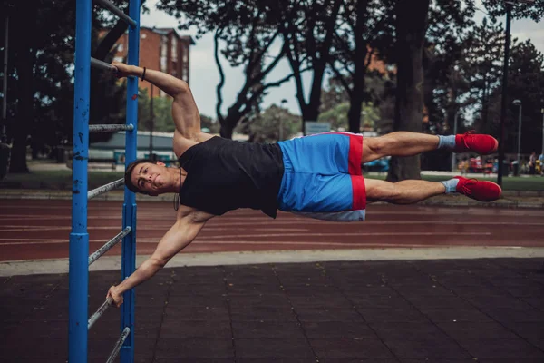 Hombre atlético haciendo asta de la bandera en el gimnasio al aire libre —  Fotos de Stock