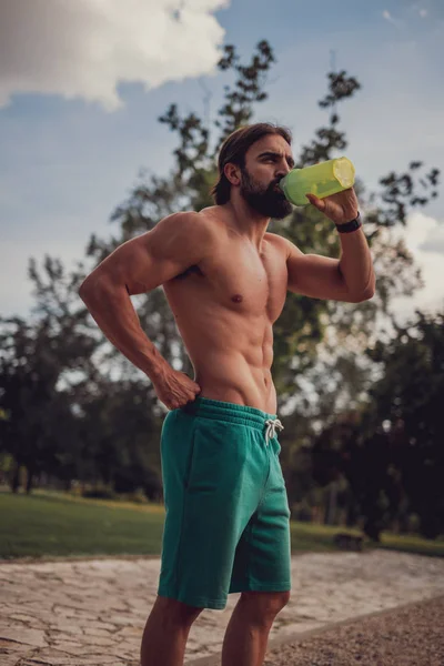 Barbudo musculoso hombre beber agua al aire libre —  Fotos de Stock