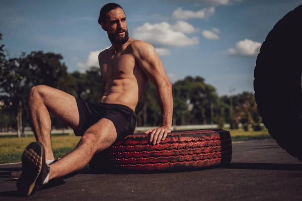 Hipster atleta descansando sobre el neumático afte entrenamiento —  Fotos de Stock