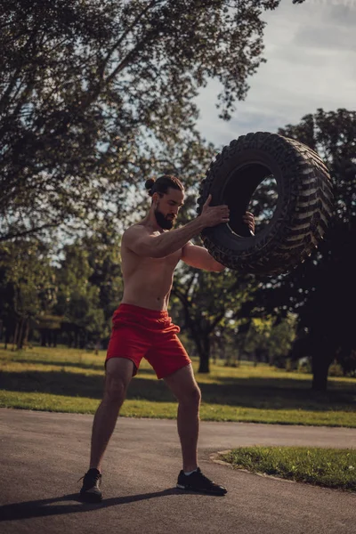 Macho atleta levantando neumático en el parque —  Fotos de Stock