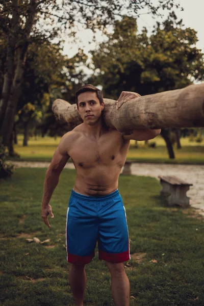 Hombre llevando leña en un gimnasio al aire libre — Foto de Stock