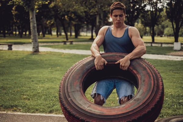 Hombre atlético entrenando con neumático en el parque —  Fotos de Stock