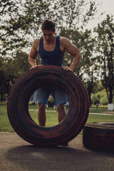 Hombre atlético volteando neumático en el parque —  Fotos de Stock