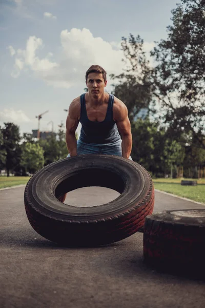Hombre atlético concentrado volteando neumático en el parque —  Fotos de Stock