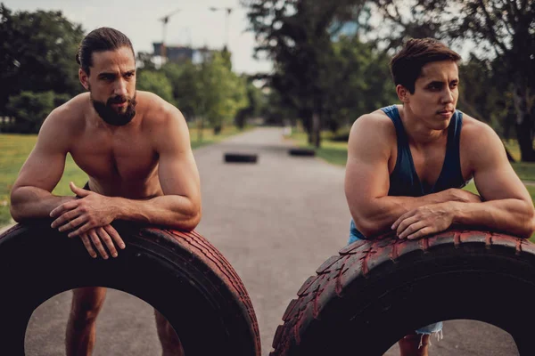 Apto homens descansando de um treino com pneus — Fotografia de Stock