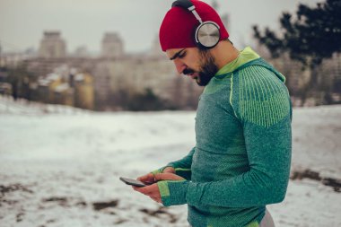 Cep telefonu kullanan ve açık havada müzik dinleyen bir sporcu