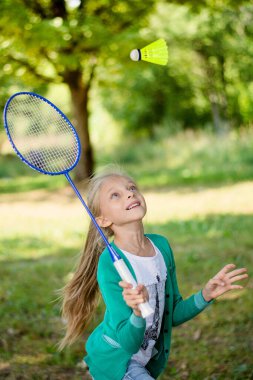 Kız piknikte badminton oynuyor.