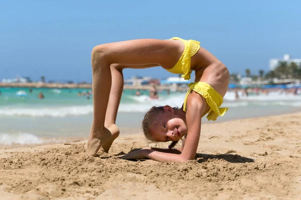 Kız plajda yoga egzersizi yapıyor.