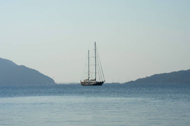 Yalnız bir yelkenli, dağların arka planında duruyor