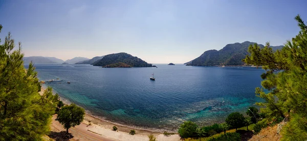 Çam dallarının arasından deniz koyunun panoramik görüntüsü. Marmaris bölgesinde deniz manzarası.