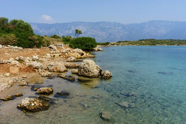 岛上的海岸在爱琴海的背景山上 大石头躺在水里 — 图库照片