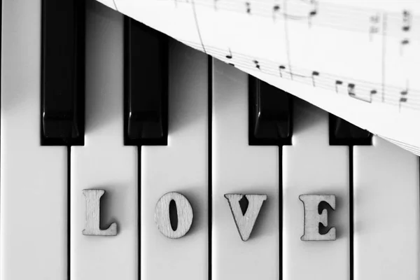 Close-up van de piano toetsen met de liefde brieven en het hart. De oorspronkelijke art afbeelding met valentine. — Stockfoto