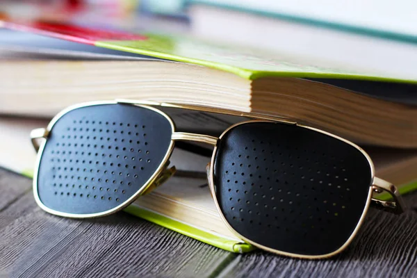 Black medical glasses with holes and book