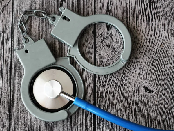 sağlık stetoskop ve ahşap arka plan üzerinde kelepçe