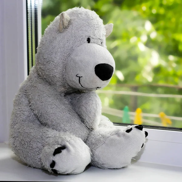 Urso polar brinquedo senta-se no peitoril da janela — Fotografia de Stock