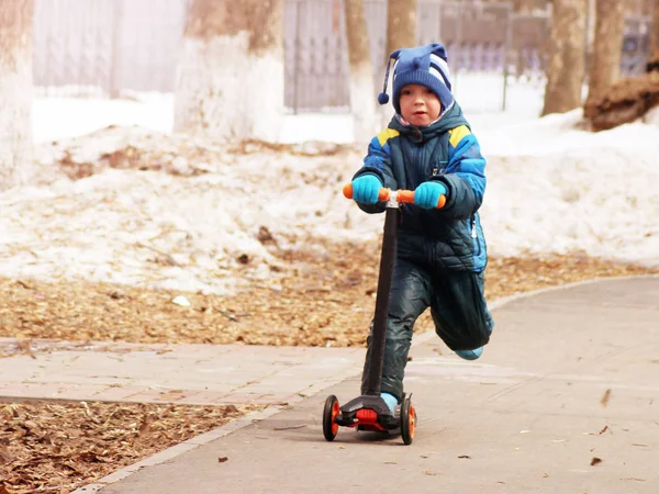 Uma criança montando uma scooter na primavera — Fotografia de Stock
