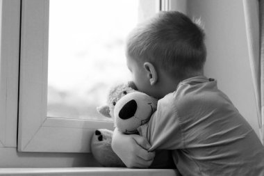 Penceredeki üzgün çocuk ve ayı oyuncağı, yalnızlık ve depresyon