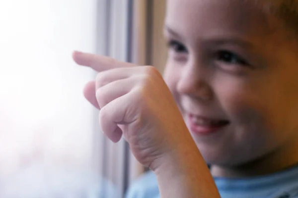 Un niño pequeño dibuja en el cristal con su dedo — Foto de Stock