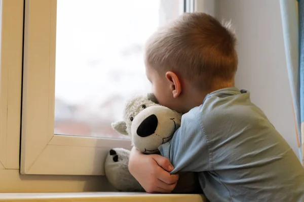 Грустный мальчик у окна и медведь игрушка, одиночество и депрессия — стоковое фото