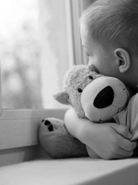 Penceredeki üzgün çocuk ve ayı oyuncağı, yalnızlık ve depresyon