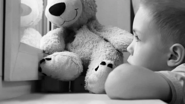 창에 슬픈 소년 과 곰 장난감, 외로움 과 우울증 — 스톡 사진