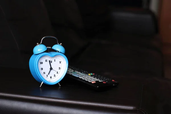 Reloj despertador azul en forma de corazón y TV remota —  Fotos de Stock
