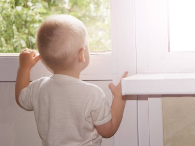 Sarışın çocuk pencereden bakar, arkadan bakar.