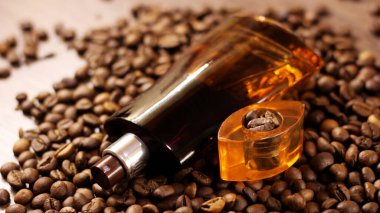 Arka planda parfüm şişesi ve kahve çekirdeği var.