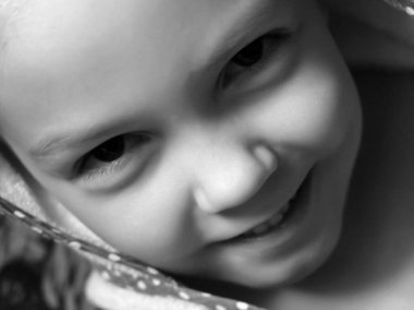 Siyah beyaz gülümseyen bir çocuğun portresi.