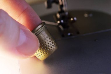 Parmağında altın bir yüksük ve dikiş makinesi