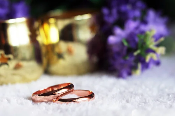 wedding details: two golden wedding rings on a purple flower petal of a wedding bouquet