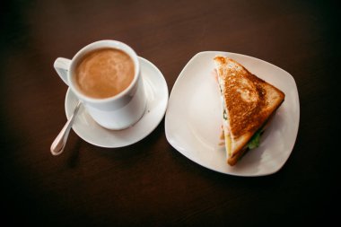 ahşap bir masa üzerinde sandviç ve Kupası kahve