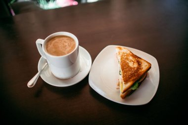 ahşap bir masa üzerinde sandviç ve Kupası kahve