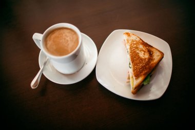 ahşap bir masa üzerinde sandviç ve Kupası kahve